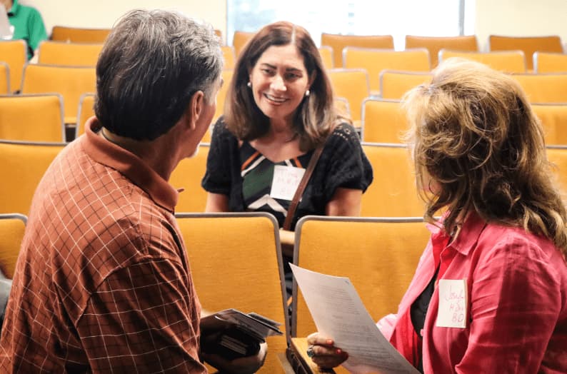 Small group of people seated and talking across rows in an auditorium